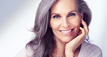 A gray-haired woman smiles to promote Mary Kay’s dedication to celebrating natural beauty at every age.
