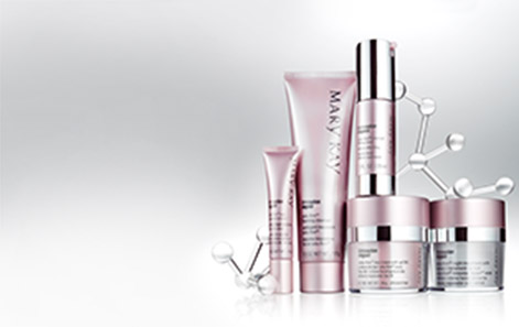 The TimeWise Repair Volu-Firm skin care set from Mary Kay is shown in front of a gray background with silver molecule-like structures behind it.