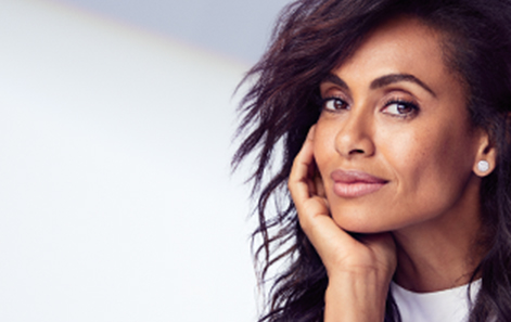 A brunette woman smiles and shows off youthful skin to promote the Mary Kay TimeWise Repair Volu-Firm set.