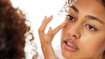 Close-up of model touching the undereye area with her finger.