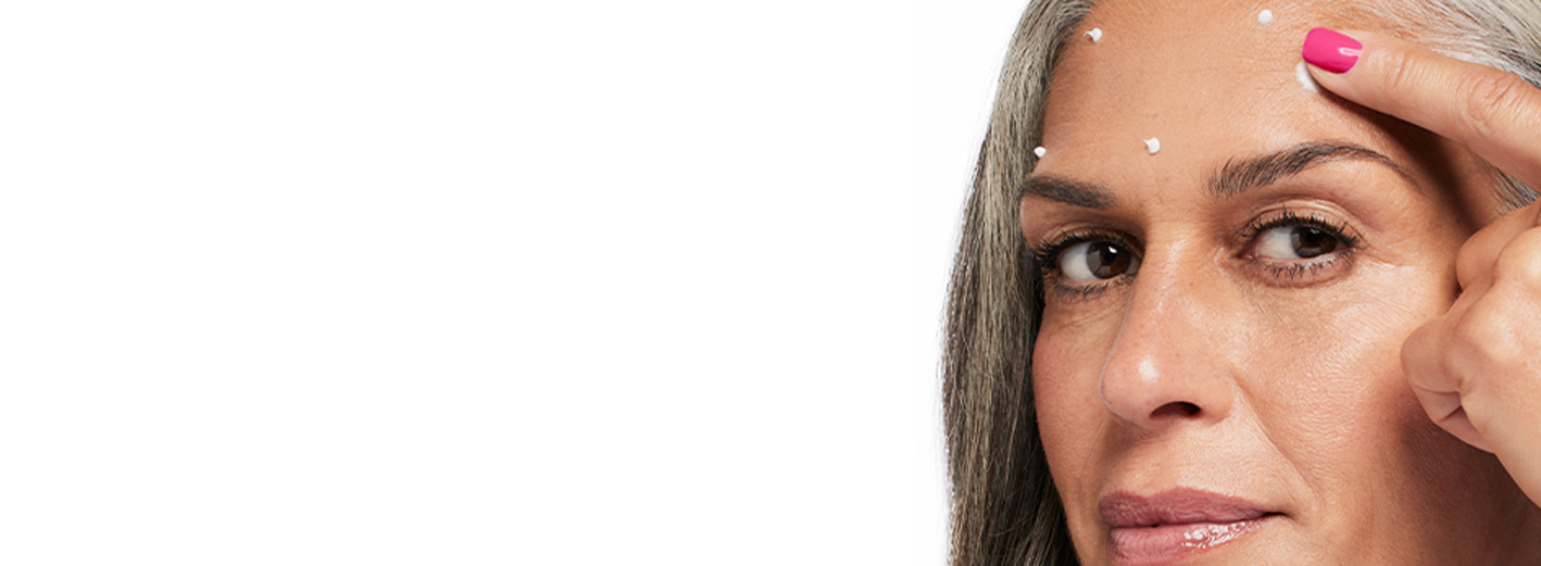 Grey-haired woman rubbing in Dynamic Wrinkle Limiter topical cream to targeted spots on her forehead