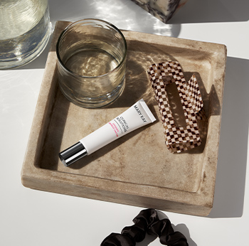 Dynamic Wrinkle Limiter on a styled marble vanity tray alongside a hair clip and glass of water