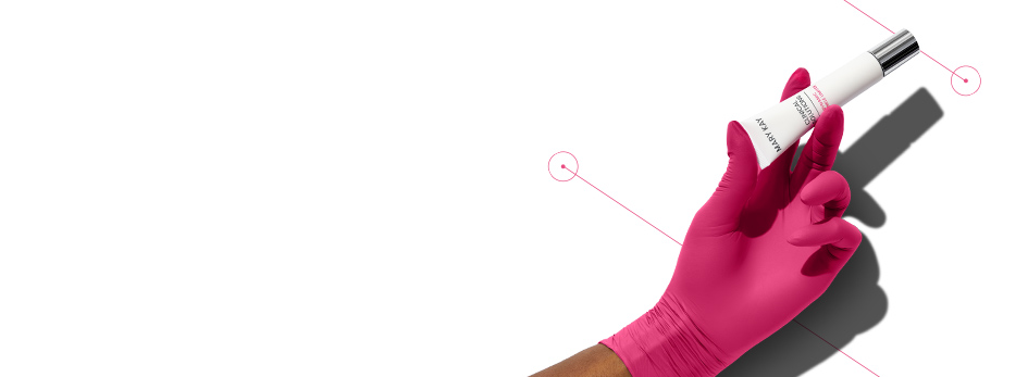 A pink medical gloved hand holding Dynamic Wrinkle Limiter topical cream in the same way one would hold an injection treatment