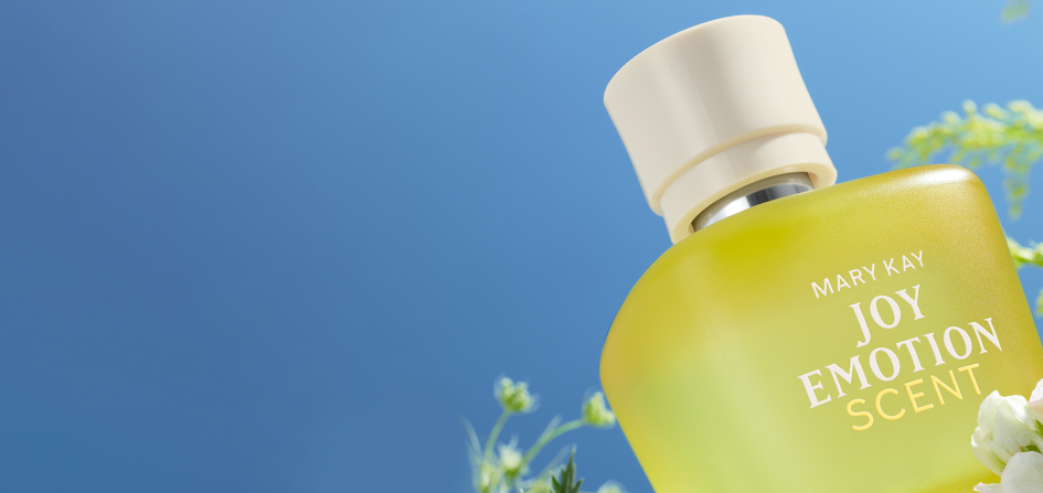 Mary Kay Joy Emotion Scent Eau de parfum yellow bottle surrounded by florals on a blue sky background